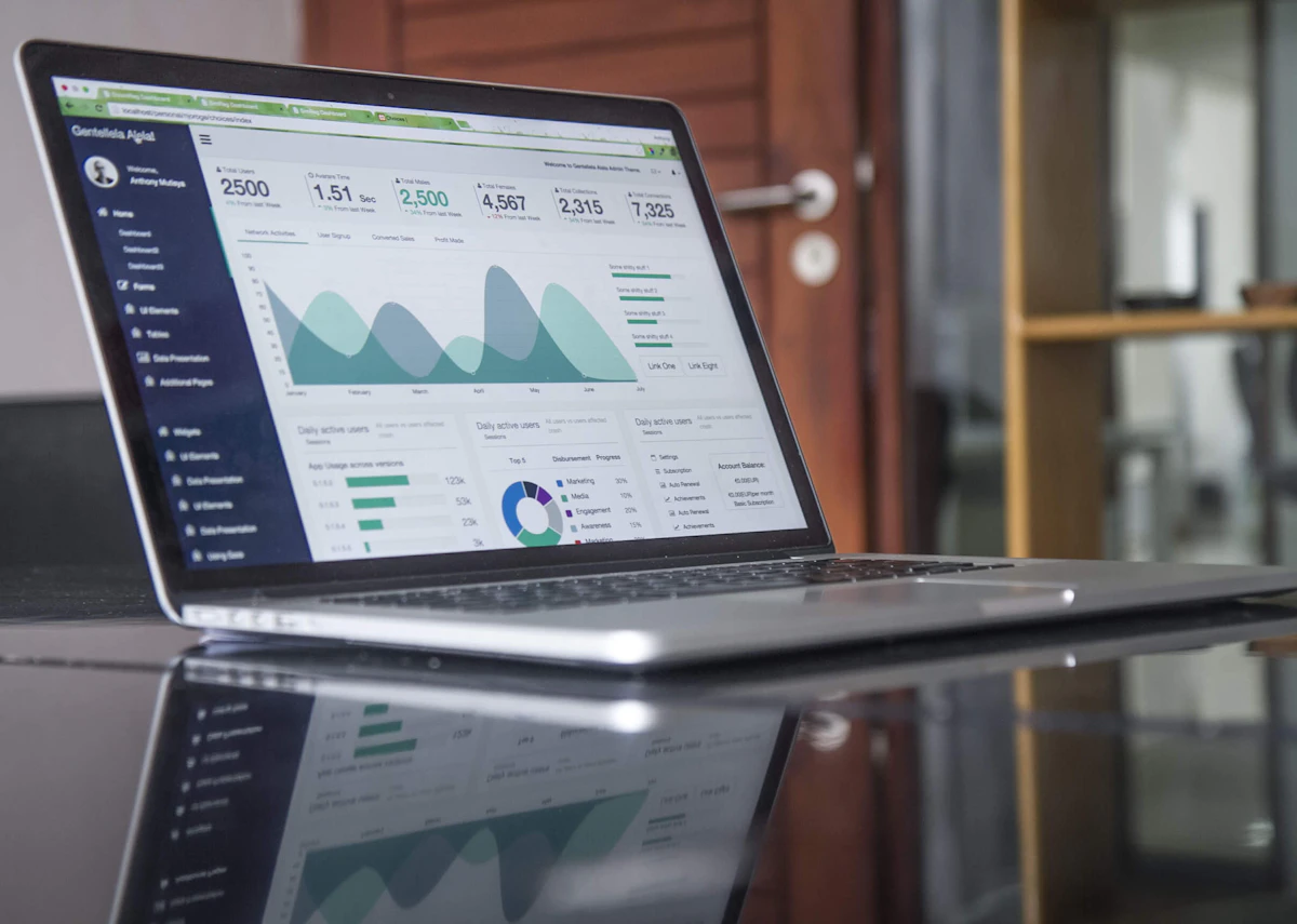 Laptop on a glossy desk showing an analytics dashboard with area and donut charts