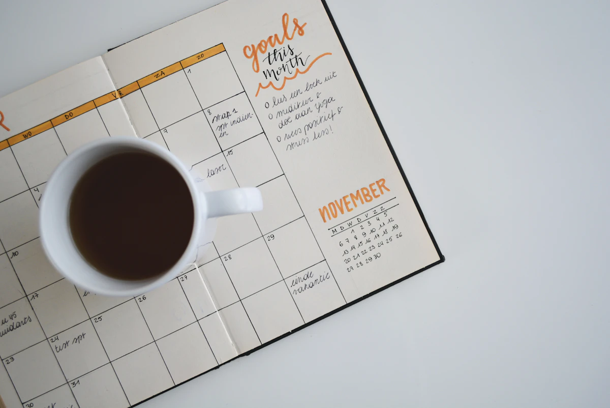 Open planner with a hand-drawn November calendar and a cup of black coffee, seen from above